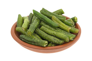 A small bowl filled with dried and salted green beans isolated on a white background.