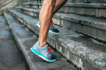Closeup of the legs of a black man running up stairs.