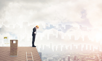 Engineer man standing on roof and looking down. Mixed media