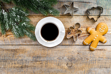 Obraz na płótnie Canvas Christmas evening. Gingerbread man, coffee and spruce branch on wooden background top view copyspace