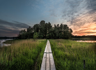 Duckboard path to the sunset. Beautiful nordic sunset landscape from Finland