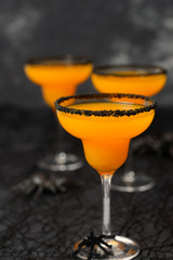 creepy Halloween cocktail, orange margarita with black sugar rim