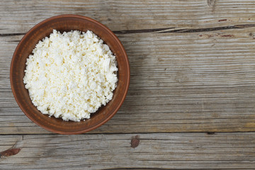 Fresh cottage cheese in a bowl on a wooden table
