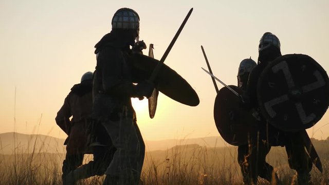 Silhouettes of Vikings warriors fighting with swords, shields. Contre-jour