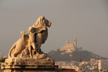lion statue in marseilles at gare saint charles and basilica of notre-dame de la garde on background - 177812686