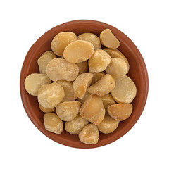 Top view of dry roasted and salted macadamia nuts in a small terracotta bowl isolated on a white background.