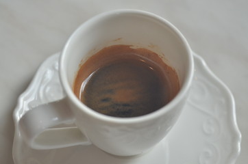 Cup Espresso (with a flower pattern on the surface) on White marble table.