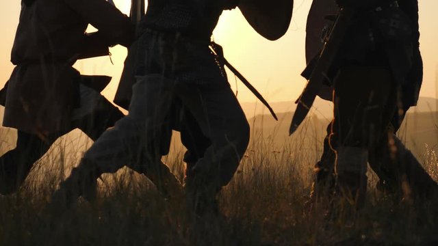 Silhouettes of Legs of Viking Warriors, fighting with swords. Contre-jour
