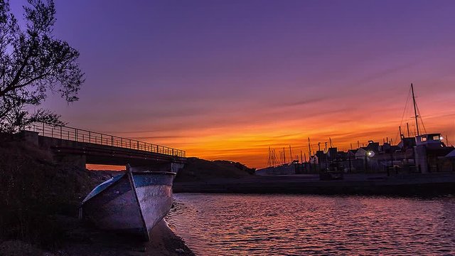 coucher de soleil sur le port de Gruissan avec barque abandonn&eacute;e en premier plan