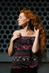 Wonderful young red haired model with freckles. Woman with closed eyes posing with naked shoulders