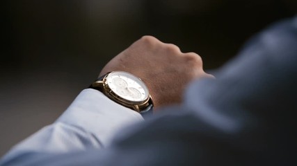 Young male business man is waiting for a meeting. Hand with a clock close up. Waits. Looks at the clock, time.