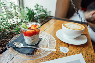 Cappuccino with spoon in cup and dessert