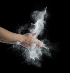 Naklejka na ściany i meble Freeze motion of dust explosion in hands isolated on black background
