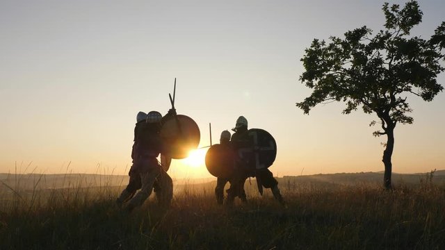 Silhouettes of Vikings warriors fighting with swords, shields. Contre-jour