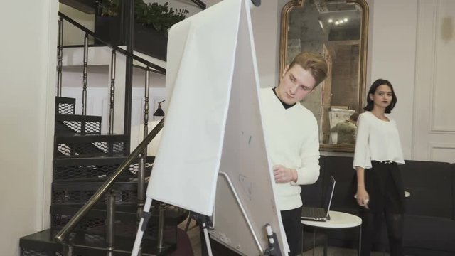 Woman explains mistakes to the man near flipchart