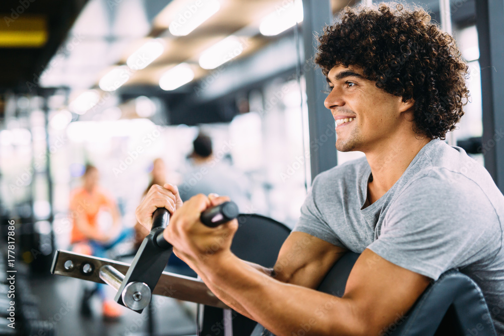 Wall mural Young handsome man doing exercises in gym