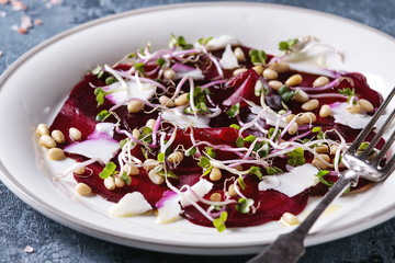 Vegetarian beetroot carpaccio salads with olive oil, goat cheese, pine nuts and sprouts in white...