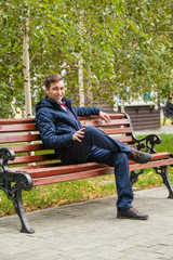 A young guy is sitting on a park bench.