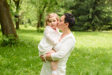 family, children and happy people concept - happy little girl hugging her mother over green background
