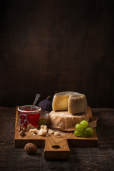 Dark still life with cheese board, fruits and wine