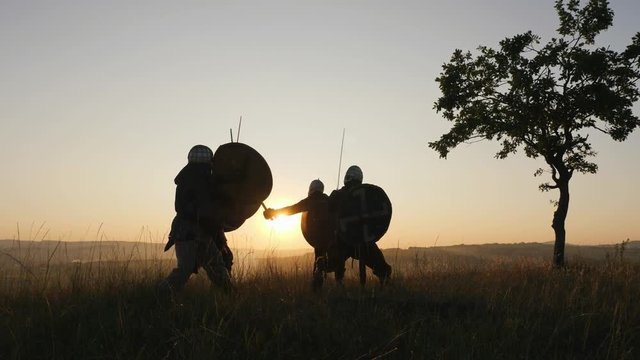 Silhouettes of Vikings warriors fighting with swords, shields. Contre-jour