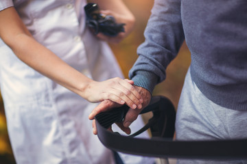 Cropped hands of nurse and senior woman holding walker