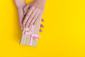 Woman hands holding present box with pink bow