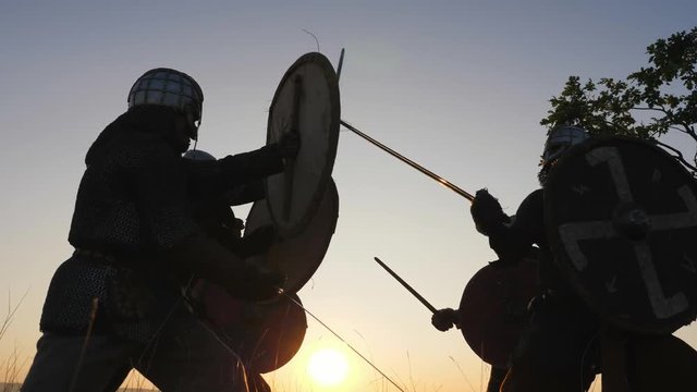 Silhouettes of Vikings warriors fighting with swords, shields. Contre-jour