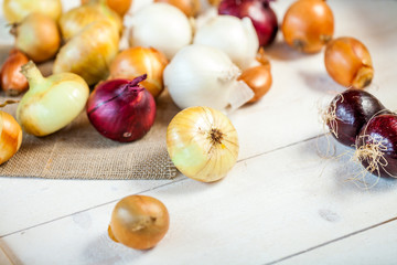 various fresh onions on a wooden table. wallpaper for grocery shopping and cooking food concept