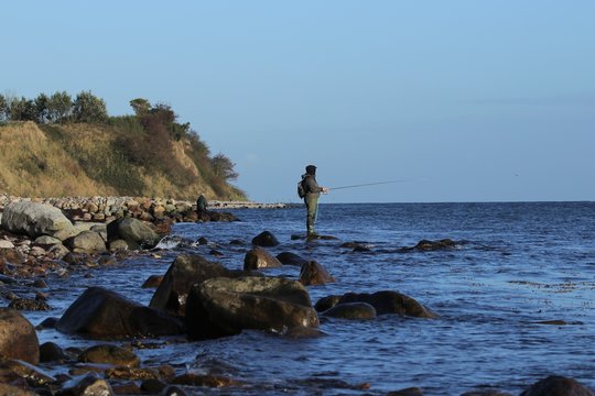 Angler in Wathose auf einem Stein, K&uuml;stenangler, Meerforelle
