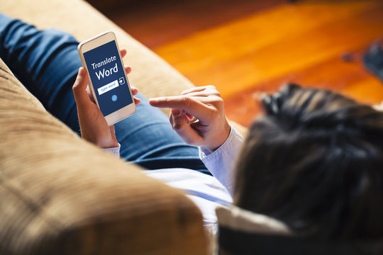 Woman using a mobile phone to translate a word while rest on a couch at home.
