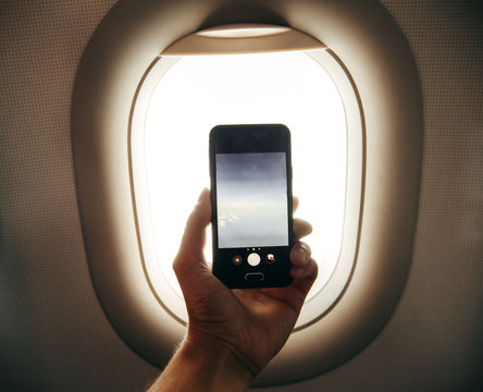 passanger makes photos on the smartphone in the plane