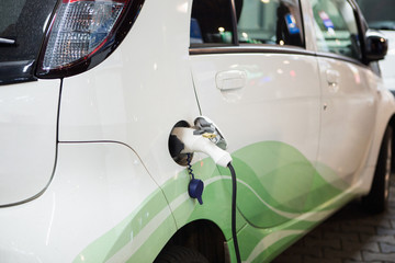 Electric car charged on a charging station by night. Close up.
