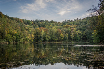Emerald Lake in Szczecin (Poland) in the autumn time, red, yellow and green leaves on the trees and the blue sky above them