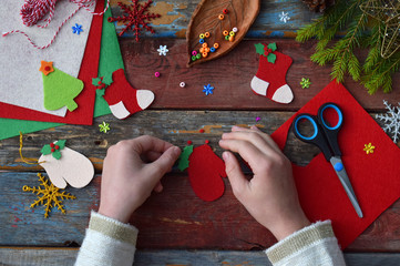 Making of handmade christmas toys from felt with your own hands. Children's DIY concept. Making xmas tree decoration or greeting card. Step 3. Decorate the toy