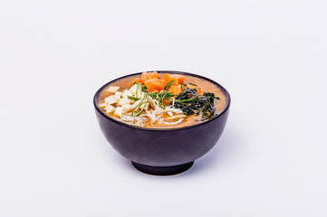 Japanese miso soup with tofu and salmon in a black bowl on a white background