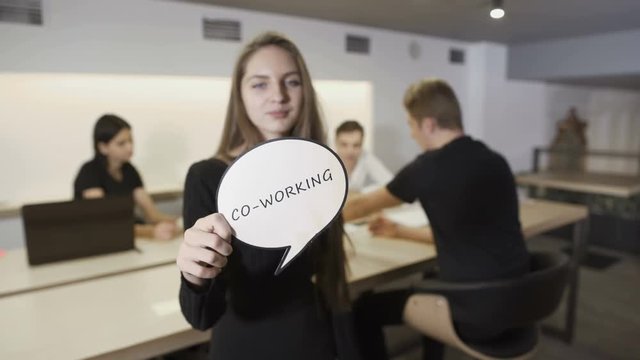 Woman with inscription "Co-working" at the background of working business team