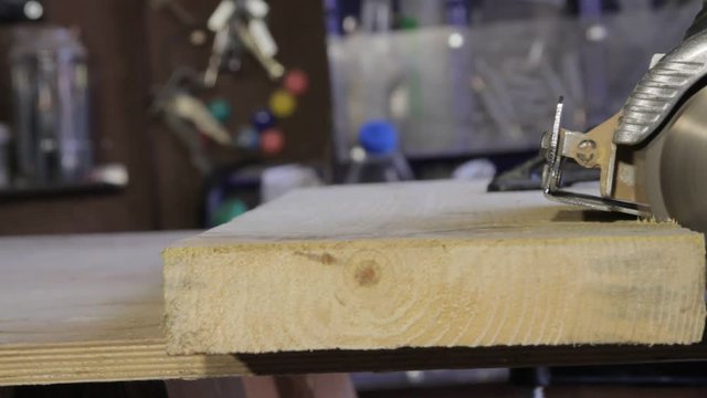 Carpenter cutting wood by circular saw
