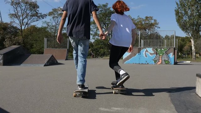 Guy and girl skateboarding in the skatepark