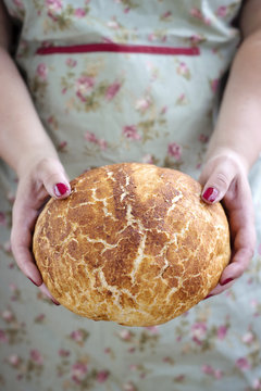 Woman holding a loaf of freshly baked rustic bread