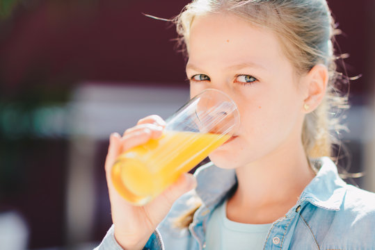 Portrait of a pretty teenage girl holding glass with tasty orange juice