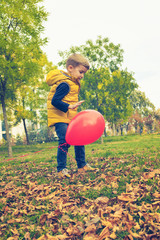 Small boy playing with balloon in nature.