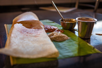Typical Indian Breakfast: Masala Dosa, Tomato Chutney, Coconut Chutney, Sambal, Vattu (all servied on a banana leaf) and a Chai - 177831230