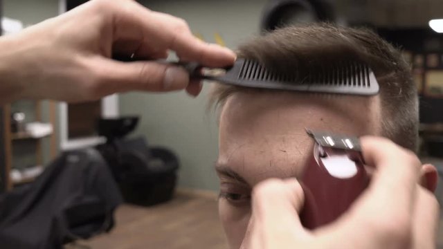 Barber works with small clipper haircuter close-up 4k.