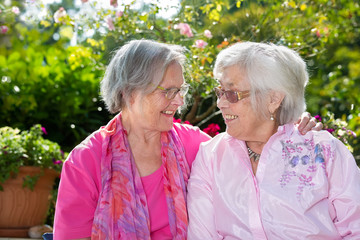 Two happy senior women chatting in garden.