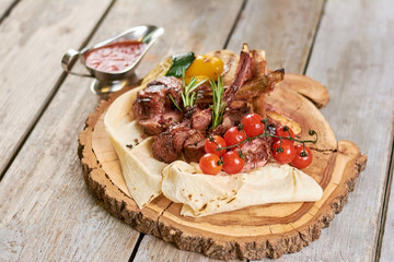 Appetizing calf ribs with cherry tomatoes. Roasted calf ribs with vegetables on platter. Organic and tasty food.