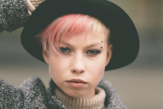 young woman with black hat and pink hair