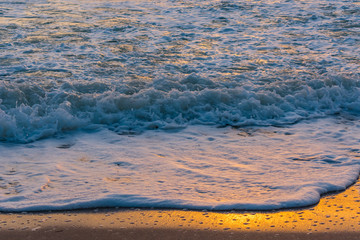background water texture - sunrise colors reflection off a wave and is spalshes on hte shore