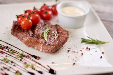 Steak ribeye with sauce from madagascar pepper.Tasty dish of restaurant with european cuisine. Appetizing food on white porcelain plate.