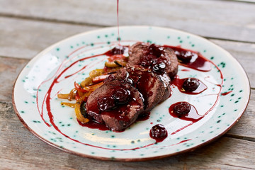Chopped beef meat with cherry sauce. Juicy veal meat on plate. Delicious dinner at european restaurant.